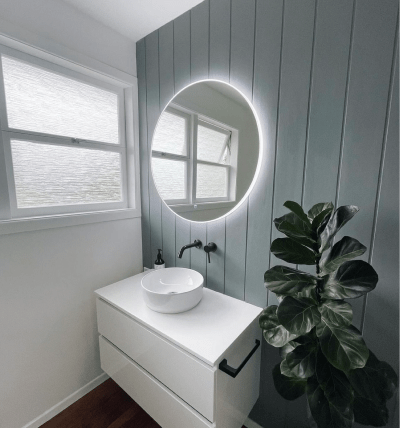 Bathroom renovation in Auckland with LED backlit mirror, textured back wall and plant.