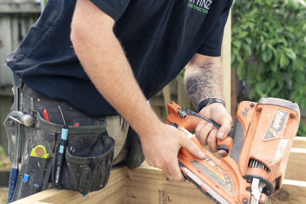 Close up of a Mainz Construction builder using a nail gun on site.